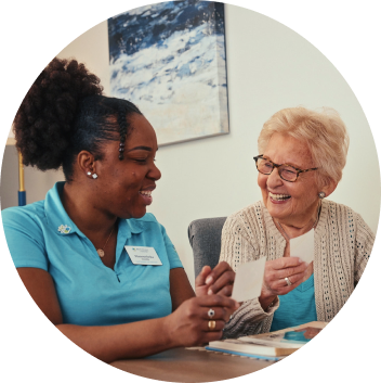 Two women smiling at each other as one of them shows another a card